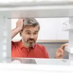 middle-aged man looking at a fridge with leak